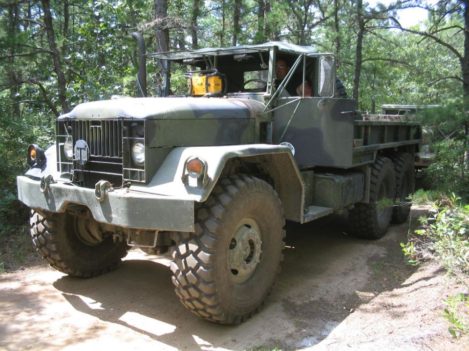 Camouflaged military truck with large tires on a dirt road