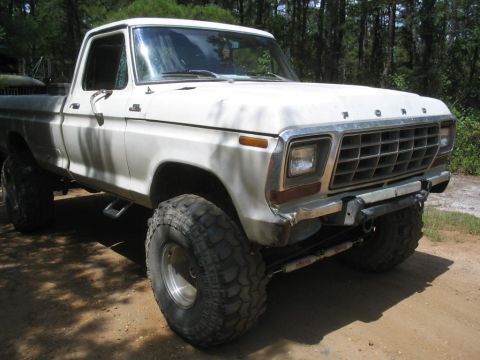 1990 Ford Bronco - This white 1979 Ford F-Series pickup truck is shown from the front quarter angle, lifted with large off-road tires.