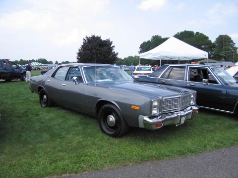 2001 Ford Crown Victoria - A 1977 Dodge Monaco sedan is parked on grass at an outdoor event with tents in the background.