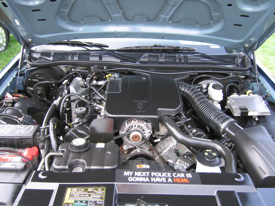 Engine bay with various hoses, wires, and components. A sticker on the underside of the hood reads 'MY NEXT POLICE CAR IS GONNA HAVE A HEMI.'