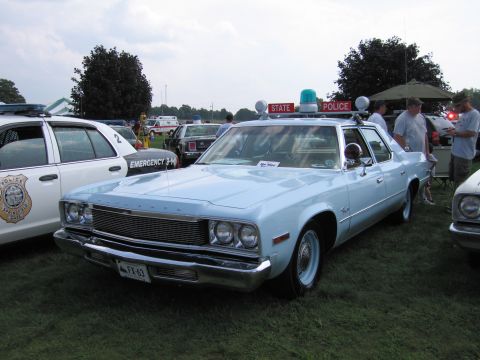 2001 Ford Crown Victoria - A light blue police car with a light bar and 'STATE POLICE' signage is displayed outdoors.