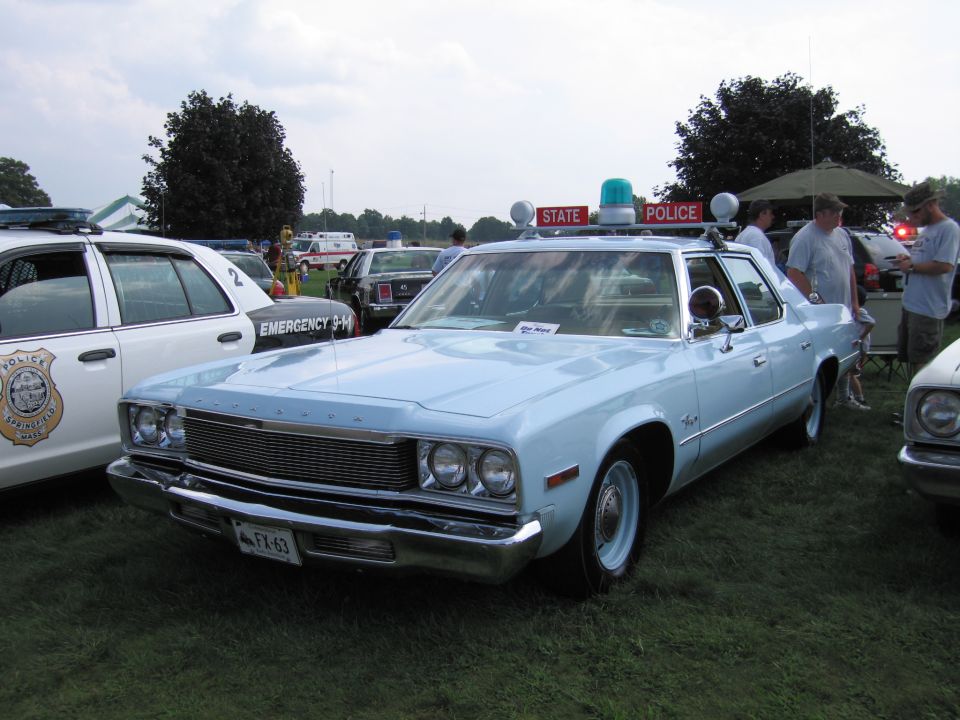 Light blue police car with 'STATE POLICE' on top, parked next to a white police car