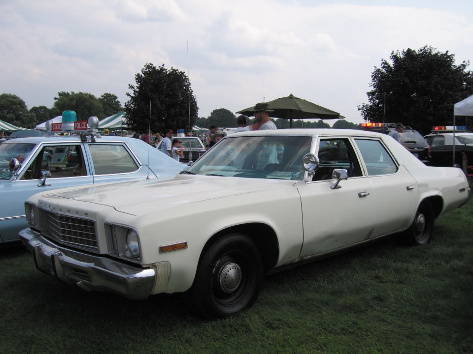 White sedan with chrome grille and bumper, parked on grass