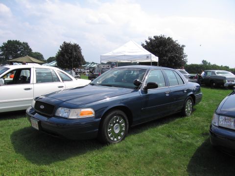 2001 Ford Crown Victoria - Dark blue 2001 Ford Crown Victoria sedan at an outdoor event with tents and other vehicles.