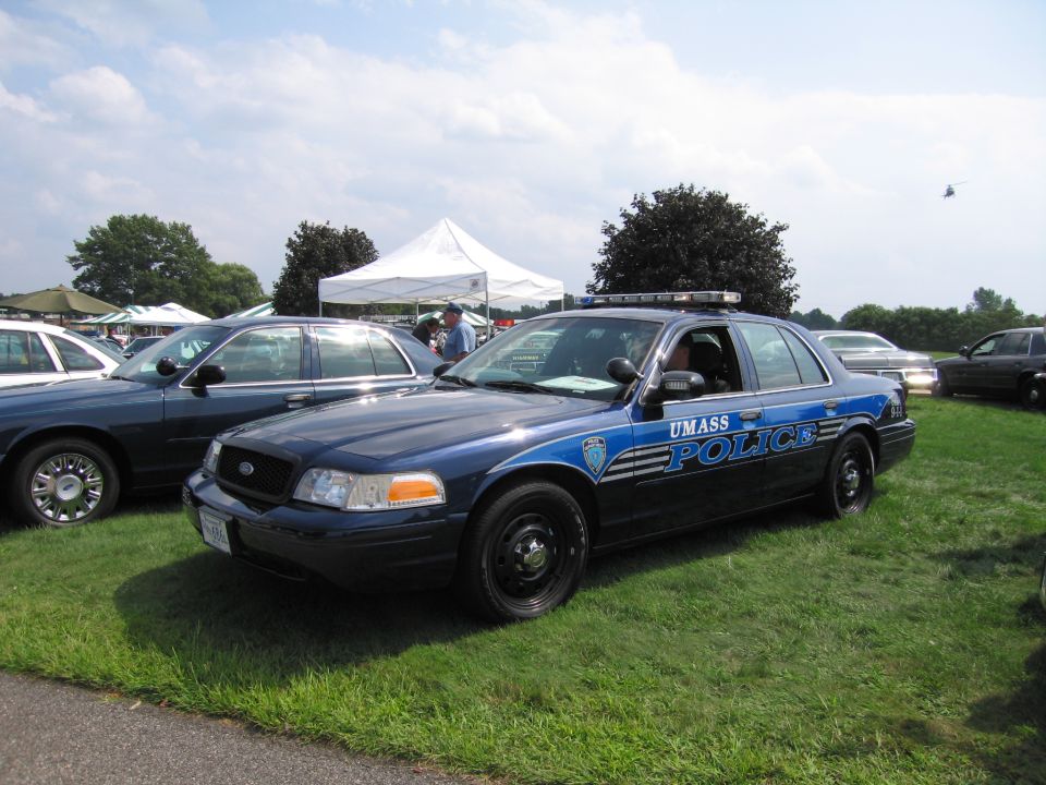 Blue police car with "UMASS POLICE" text, parked on grass