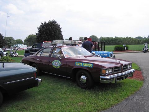 2001 Ford Crown Victoria - A maroon police car, marked "STATE PATROL", is parked on a grassy area next to other vehicles.