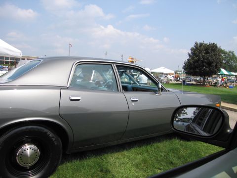 2001 Ford Crown Victoria - A gray sedan is parked on a grassy field with tents and people in the background.