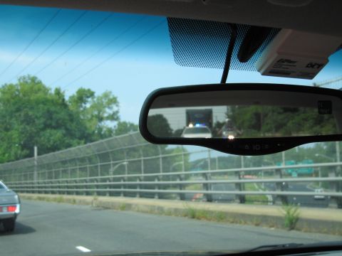 2001 Ford Crown Victoria - A police car with its emergency lights on is visible in the reflection of a rearview mirror.
