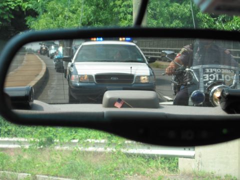 2001 Ford Crown Victoria - Reflection in rearview mirror shows a police car and motorcycle in traffic. The police car appears to be a 2001 Ford Crown Victoria.