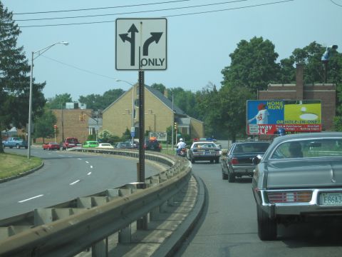 2001 Ford Crown Victoria - Cars driving on a road with a directional sign and a billboard in the background.