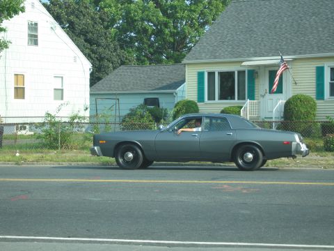2001 Ford Crown Victoria - A gray sedan is parked on the side of the road in front of a residential house.