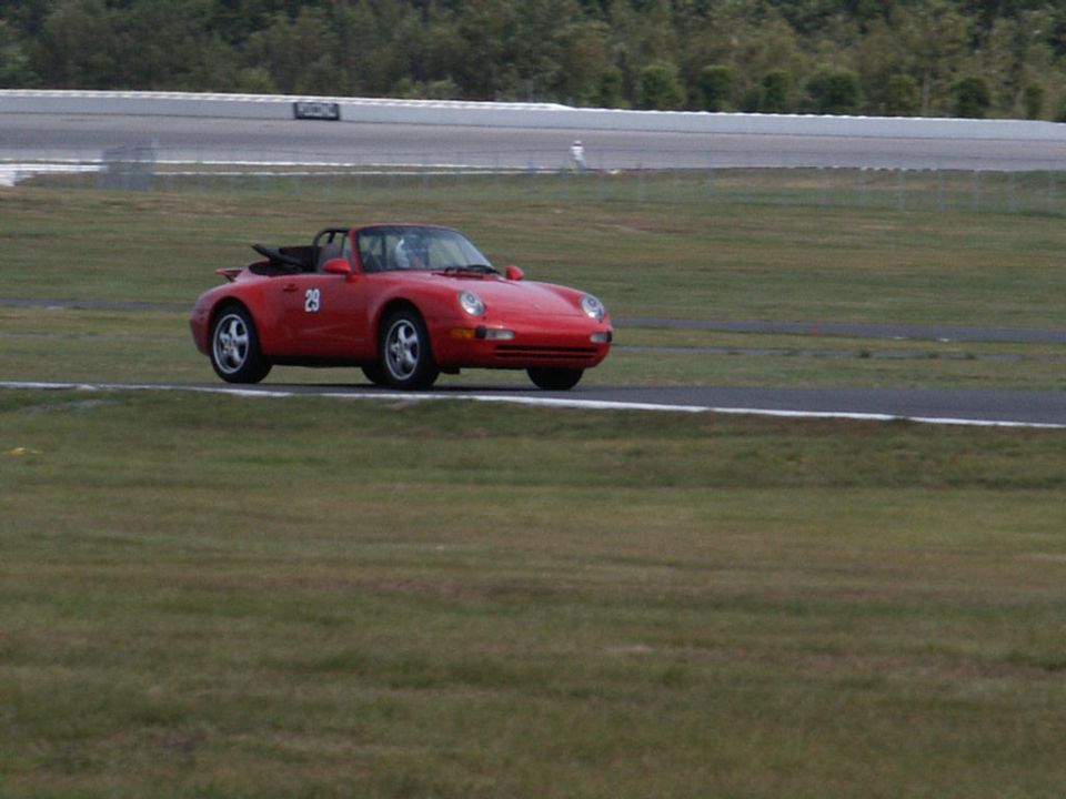 Red convertible sports car with number 29 on door, on a race track