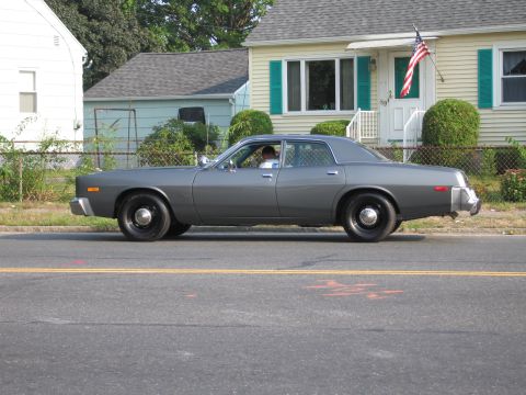 2001 Ford Crown Victoria - A gray late-1970s full-size four-door sedan driven along a suburban street, shown in side profile on black steel wheels with small dog-dish…