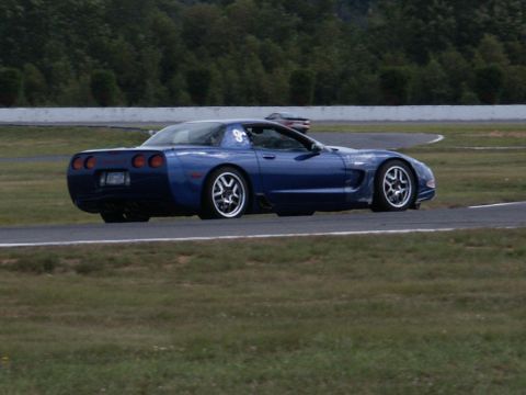 2001 Mercury Grand Marquis - A blue Chevrolet Corvette is seen on a race track, with another vehicle visible in the distance.