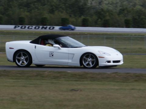 2001 Mercury Grand Marquis - A white convertible sports car with a black top and the number 12 on its side is seen on a race track, with another car in the background.
