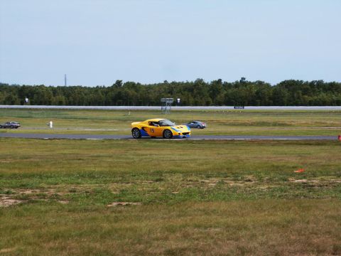 2001 Mercury Grand Marquis - Two cars on a race track with a wooded area in the background under a cloudy sky.