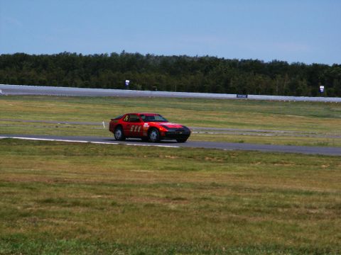 2001 Mercury Grand Marquis - A red sports car with the number 611 is seen on a race track under a clear blue sky.