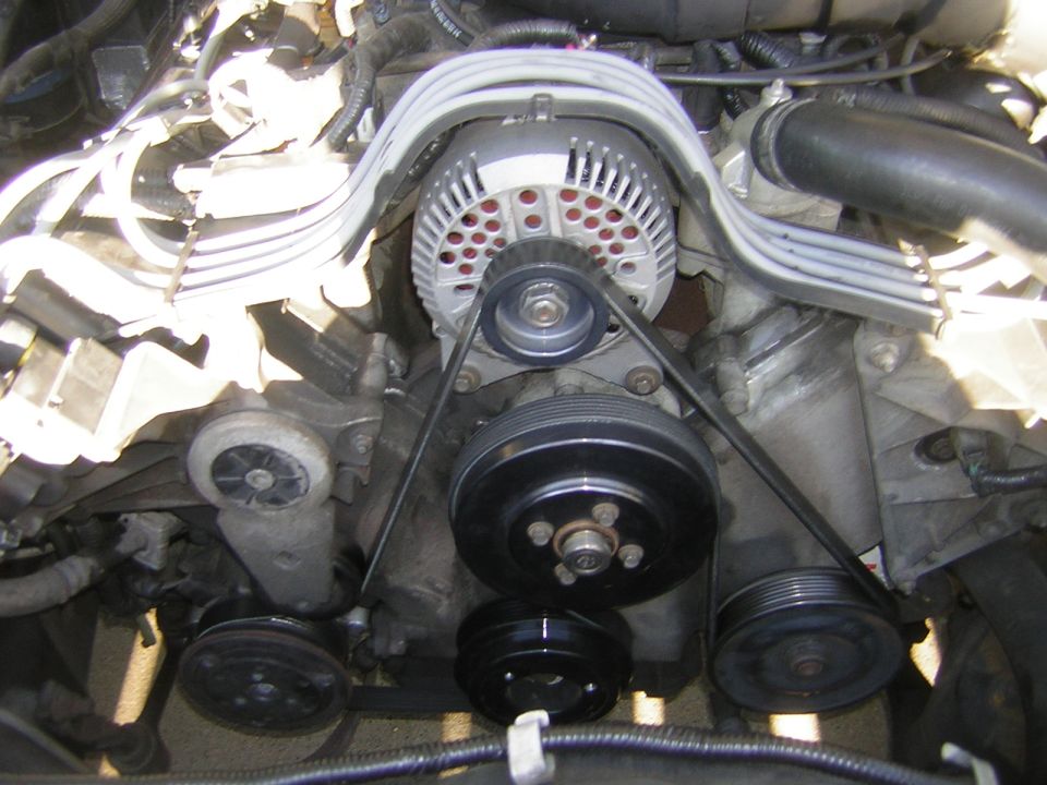 Engine bay close-up showing alternator, black serpentine belt and pulleys