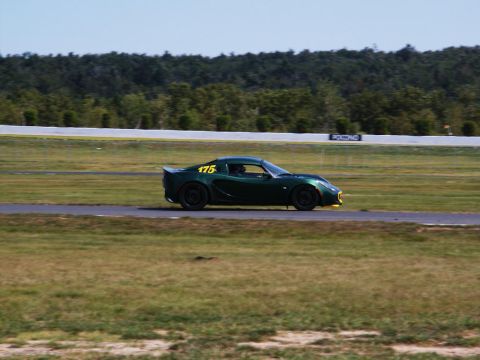 2001 Mercury Grand Marquis - A green sports car with racing numbers drives on a track with trees in the background.