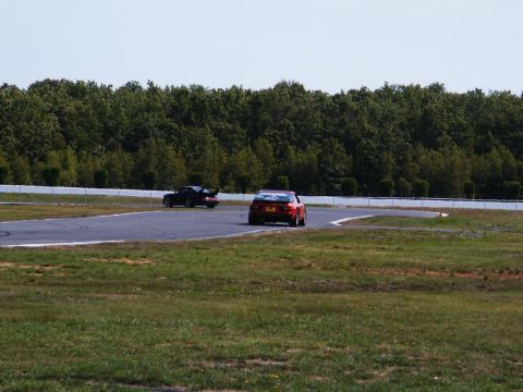 2001 Mercury Grand Marquis - Two cars race on a track surrounded by trees and grass.