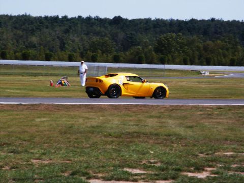 2001 Mercury Grand Marquis - A yellow sports car is on the track, with a person in white standing in the background.