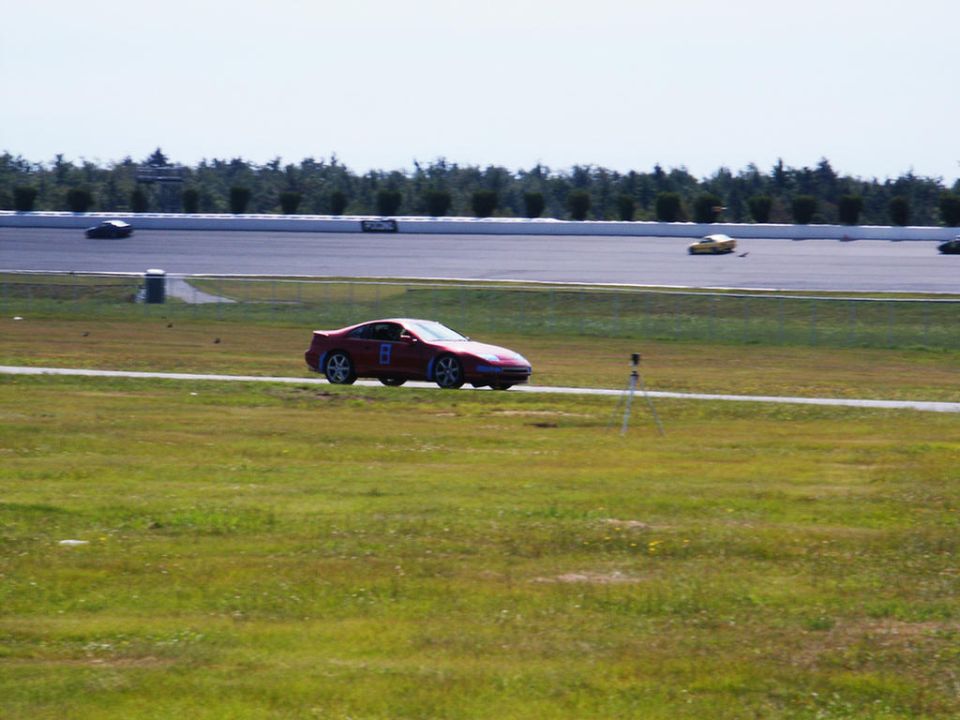 Red coupe with racing number 8 on door, driving on a racetrack