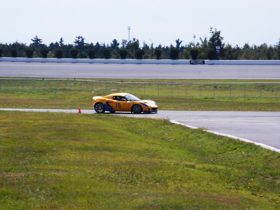Yellow sports car with blue accents and number 15 on the door, driving on a race track
