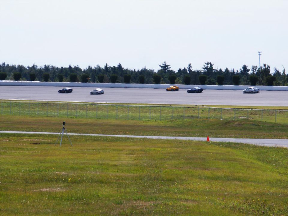 Several cars racing on a track with trees in the background