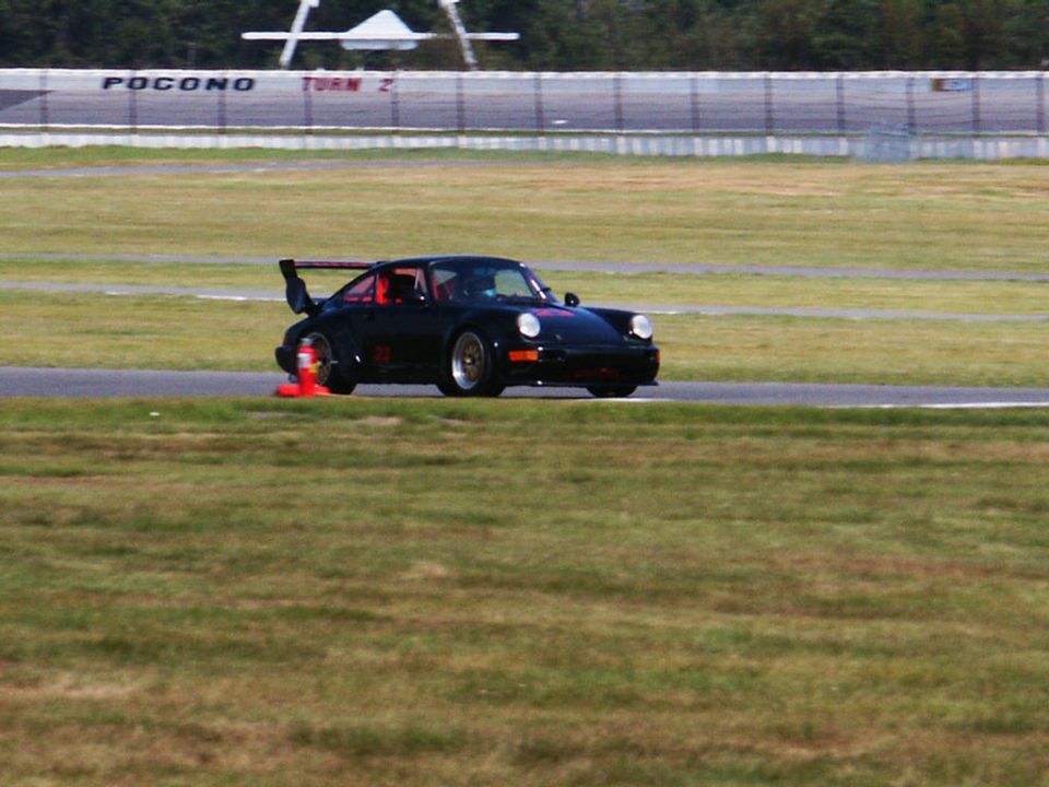 Black Porsche 911 with a large rear spoiler on a race track