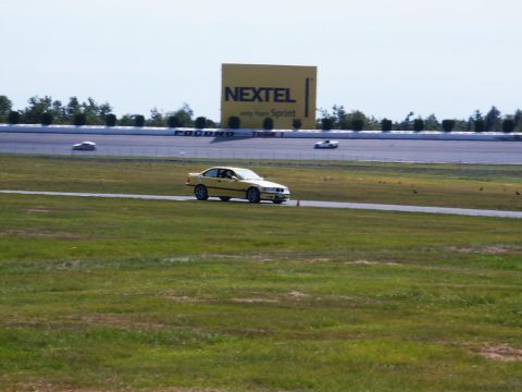2001 Mercury Grand Marquis - A yellow BMW E36 sedan navigates a turn on a race track, with a large Nextel billboard visible in the distance.