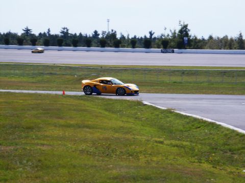 2001 Mercury Grand Marquis - A yellow sports car races on a track, with another vehicle visible further down the course.