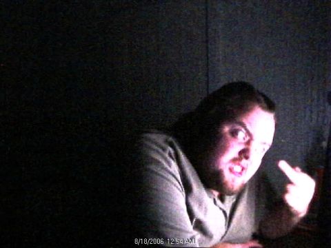 1985 Ford Crown Victoria LTD - A man is captured in a dimly lit photo, making an offensive gesture with his hand.