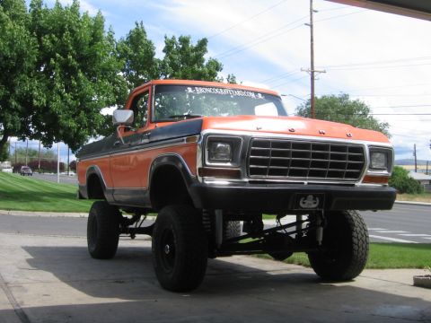 1979 Ford Bronco - This lifted 1979 Ford Bronco features a two-tone orange and black paint scheme and a prominent "BRONCOGRAVEYARD.COM" sticker.