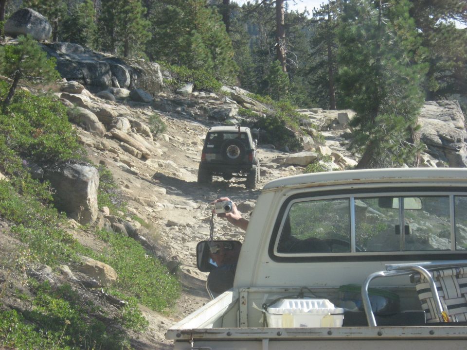 Two off-road vehicles navigate a rocky mountain trail