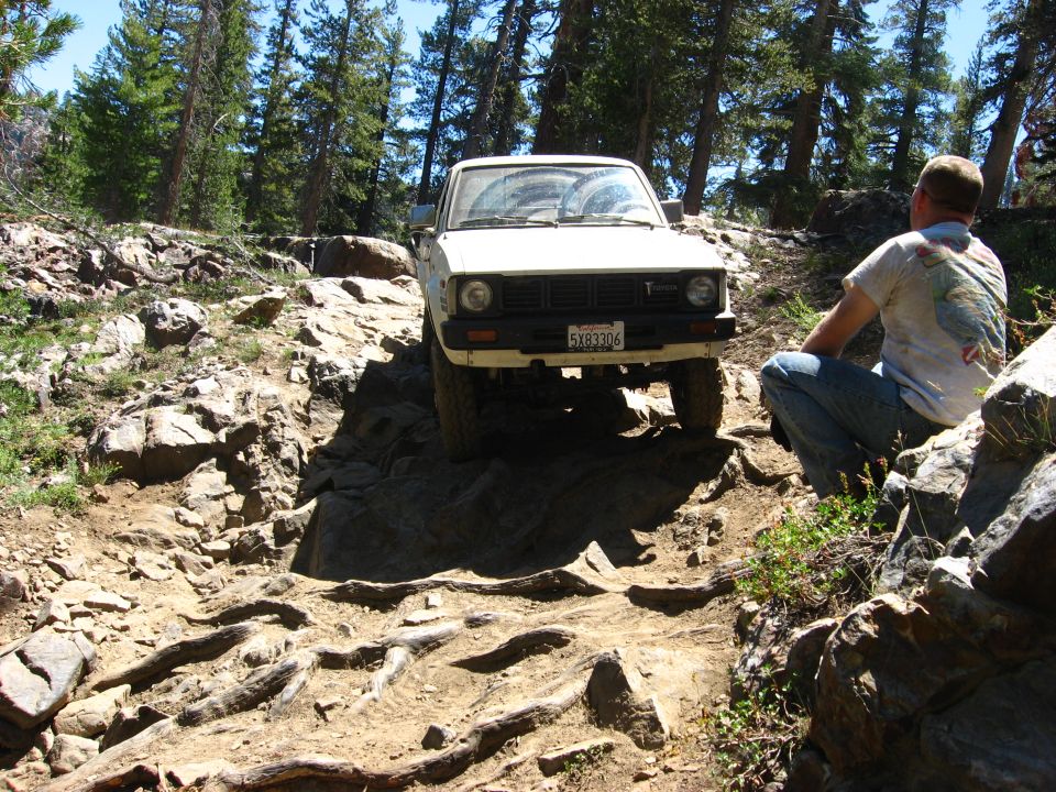 White pickup truck navigating a difficult rocky trail. License plate reads 5X93306