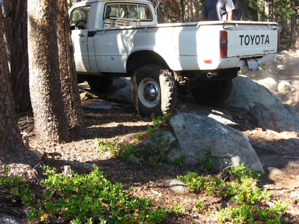 White Toyota pickup truck navigating rocks on a trail