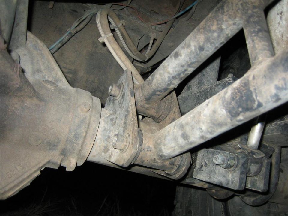 Close-up of a vehicle's front suspension, showing the differential housing, control arms, and sway bar links