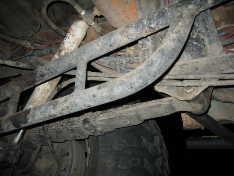1991 Ford Bronco - The undercarriage of a vehicle, suspension components and a large tire, with visible wiring and metal framing.