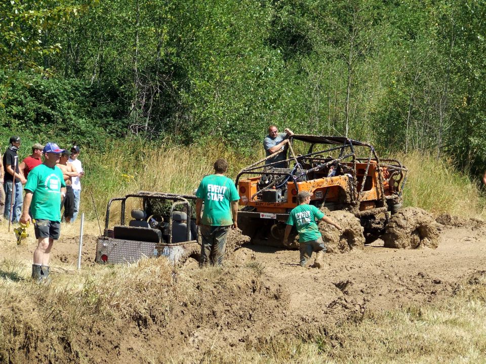 Two off-road vehicles stuck in mud with people around