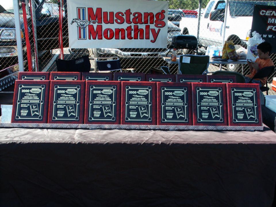 Row of 2006 event winner plaques on a table, Mustang Monthly banner behind