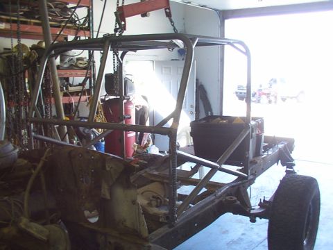 1978 Ford Bronco - Vehicle frame with a custom roll cage being installed, suspended by a shop crane.