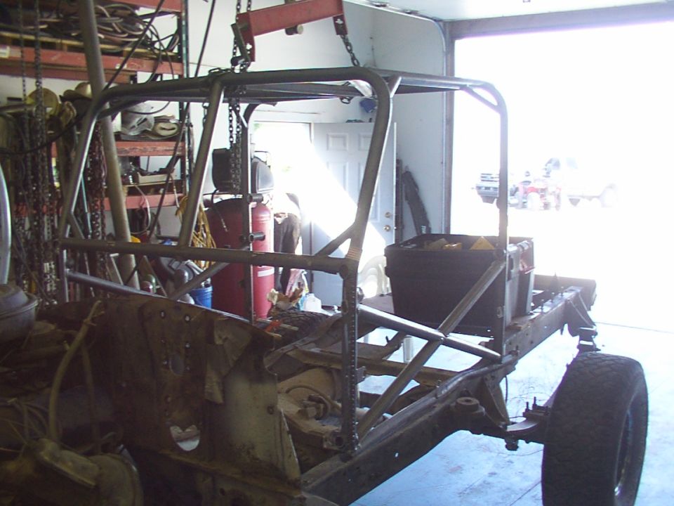 Roll cage being welded onto vehicle frame in garage