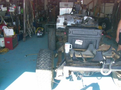 1978 Ford Bronco - Vehicle frame and engine assembly in a garage, with tires and tools around.