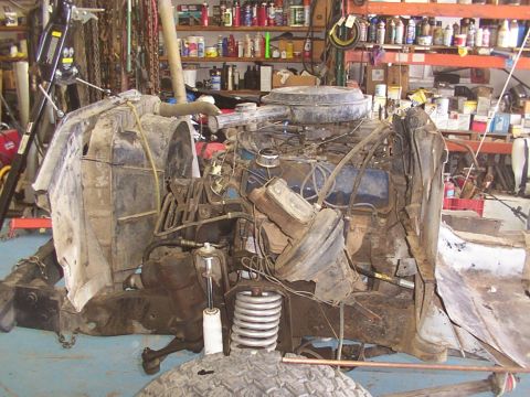 1978 Ford Bronco - Front end of a vehicle disassembled, showing engine and suspension components in a workshop.