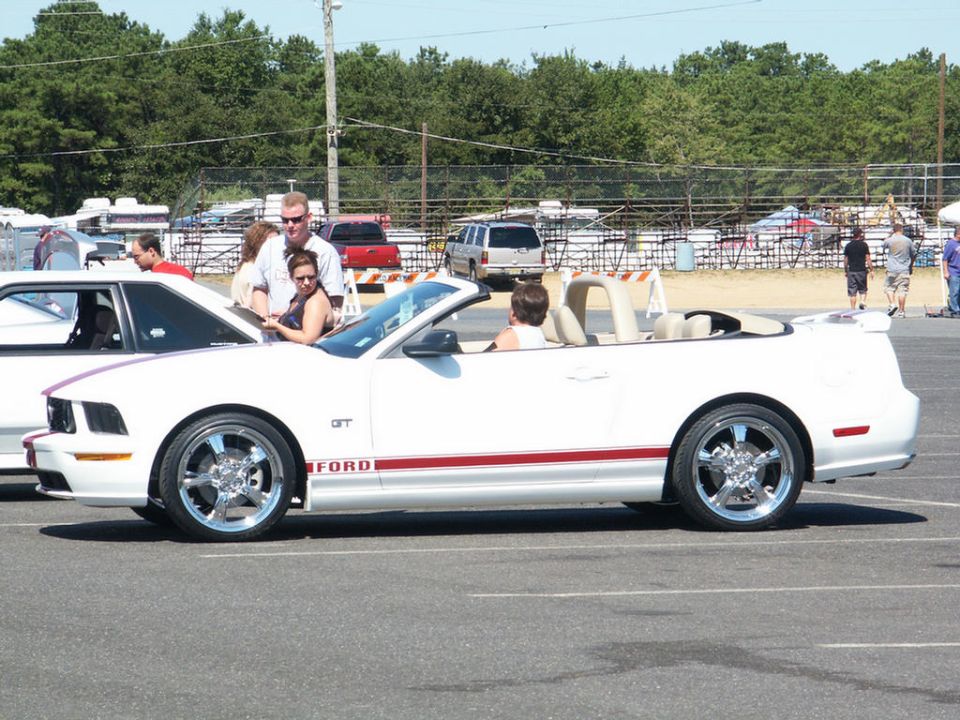 White convertible Ford Mustang GT with red stripe and GT badging, side view