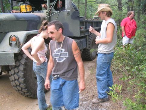 1990 Ford Bronco - Several people are gathered around a large military truck in a wooded setting.