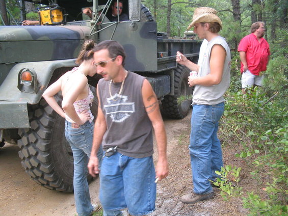 Military truck with people standing around it in a wooded area