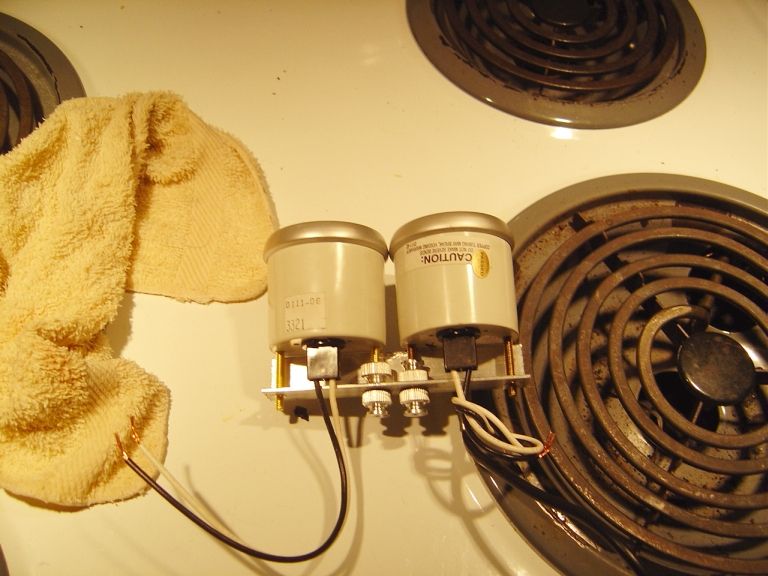Back of two round gauges on a shared bracket with wiring, resting on a stovetop