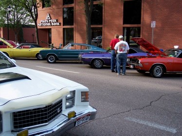 1972 Ford Ranchero - Several classic cars are parked along a street in front of a bank building.