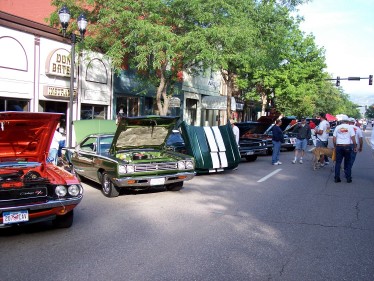 1972 Ford Ranchero - A street fair or car show with multiple classic vehicles on display.